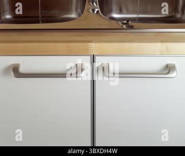 Schließen Sie die Griffe eines Küchenschranks mit Waschbecken Stockfoto