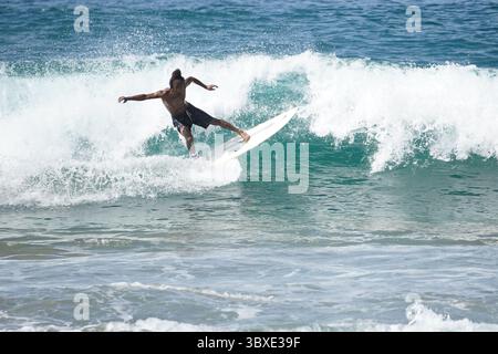 Surfer, der eine perfekte Welle an einem abgelegenen Strand fährt und das Wesen von Freiheit, Abenteuer und Verbindung mit der Natur festnimmt. Ein kraftvoller Moment des Surfens Stockfoto