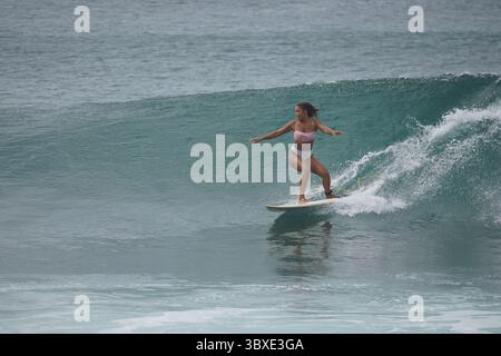 Surfer, der eine perfekte Welle an einem abgelegenen Strand fährt und das Wesen von Freiheit, Abenteuer und Verbindung mit der Natur festnimmt. Ein kraftvoller Moment des Surfens Stockfoto