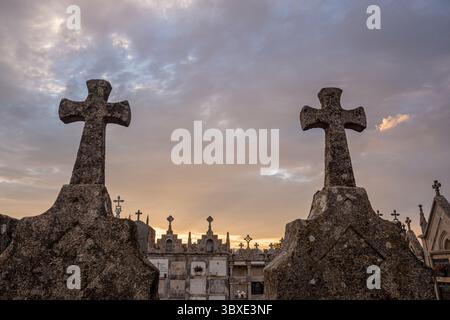 Silhouette christlicher Kreuze auf einem Friedhof während einer bunten Dämmerung. Stockfoto