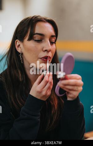 Frau, Die Lippenstift Aufträgt, Während Sie Den Kleinen Kompaktspiegel Verwendet Stockfoto