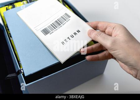 Die Hand einer Frau hält ein Rücksendeetikett über der blauen Box. Hochwertige Fotos Stockfoto