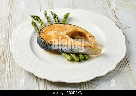 Ein Gourmet-Gericht besteht aus einem wunderschön gegrillten Lachssteak und frischem grünen Spargel Stockfoto