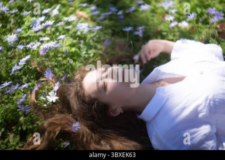 Eine ruhige junge Frau liegt sanft in einem pulsierenden Feld voller schöner Blumen Stockfoto