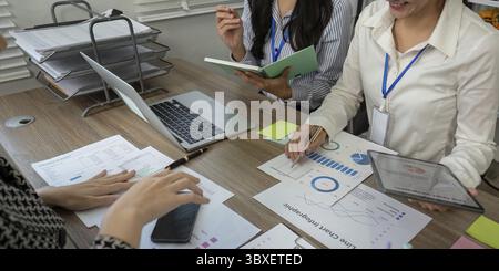 Eine vielfältige Gruppe von Fachleuten führte an einem Konferenztisch eine lebhafte Diskussion durch, analysierte Datendiagramme und Brainstorming-Strategien Stockfoto