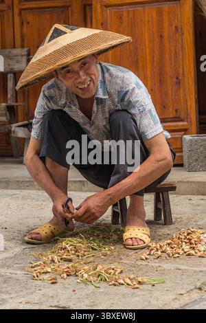 23. Mai 2013, Furong, Provinz Hunan, China: Ein Chinese mit konischem Hut schneidet kleine Zwiebeln zum Kochen in der antiken Stadt Furong, China. (Kreditbild: © Jon G. Fuller/VW Pics via ZUMA Press Wire) Stockfoto