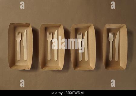 Umweltfreundliches Einweggeschirr. Biologisch abbaubare braun gefärbte Handwerk Gerichte, wie z. B. vier Container und bambus holz Besteck stehen auf einem Braunen Stockfoto