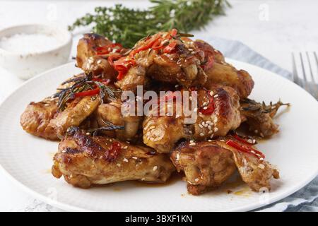 Grillhähnchenflügel. Slow Cooker süß und würzig. Im Ofen gebackener marinierter Chiken auf dem Teller in roter bbq-Sauce. Warme koreanische Küche. Seitenansicht, Nahaufnahme Stockfoto