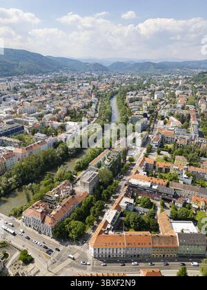 Aus der Vogelperspektive auf die Mur, die sich durch das Herz der Stadt schlängelt, gesäumt von Bäumen und Gebäuden, die Schatten im sanften Licht werfen, Graz, Steiermark, Österreich. Stockfoto
