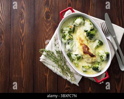 Hähnchenbrustfilet überbacken mit Broccoli in bechamelsauce Soße auf einem dunklen Holztisch. Gesunde Nahrung, sauberes Essen, Ansicht von oben, kopieren Raum Stockfoto