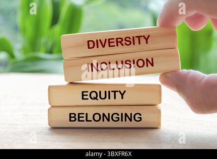 Handauflage Kultivieren von Vielfalt, Inklusion, Gleichheit und zugehörigem Text auf Holzblöcken. D- und I-Konzept Stockfoto