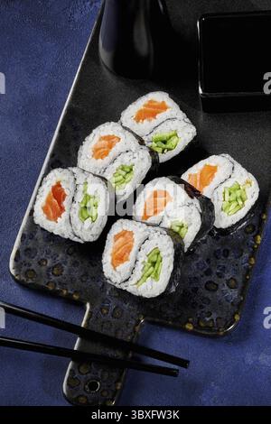 Frisch zubereitete Uamaki-Sushi-Brötchen, gefüllt mit Lachs und Gurke, präsentiert auf einem stilvollen Serviertablett mit Sojasauce, bereit zum Genießen Stockfoto