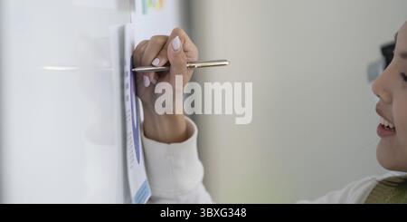 Ein Finanzexperte schreibt Notizen auf ein Whiteboard, um Steuerstrategien und Finanzanalysen zu skizzieren Stockfoto
