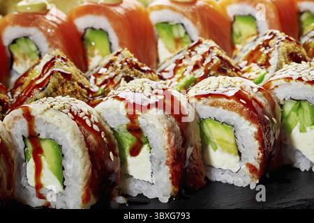 Detaillierte Nahaufnahme der appetitlichen Uamaki-Brötchen mit Aal mit herzhafter Unagi-Sauce und Sesamsamen, serviert auf schwarzem Schieferbrett. Lebendiger Jap Stockfoto