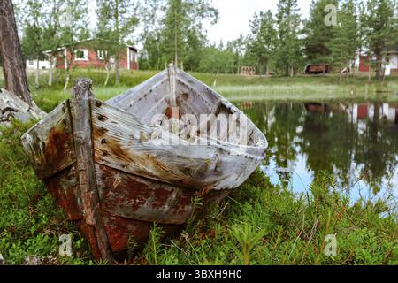 Verlassenes Holzboot im borealen Nordwald in der Nähe des Sees im Sommer Stockfoto