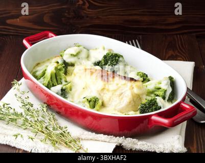 Hähnchenfilet gebacken mit Brokkoli in Bechamelsauce auf einem dunklen Holztisch. Gesundes Essen, saubere Ernährung, Seitenansicht Stockfoto