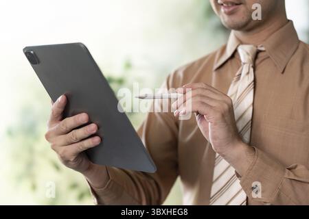 Geschäftsleute, die ein Tablet mit Eingabestift in einer modernen Büroumgebung verwenden und sich für digitale Zusammenarbeit einsetzen Stockfoto