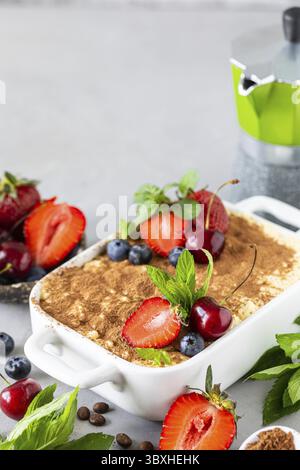 Essen, Tiramisu dekoriert mit Erdbeeren, Kirschen und Minze auf weißem Hintergrund Stockfoto