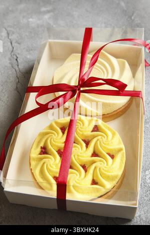 Köstliche Minitörtchen gelb und weiß mit Nüssen und Pudding in der Geschenkbox. Auswahl an köstlichen und farbenfrohen Desserts, Zitronenmelisse, Sahnetorten Stockfoto