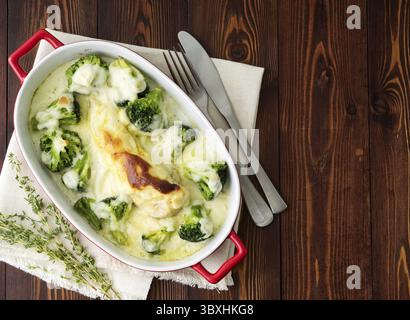 Hähnchenbrustfilet überbacken mit Broccoli in bechamelsauce Soße auf einem dunklen Holztisch. Gesunde Nahrung, sauberes Essen, Ansicht von oben, kopieren Raum Stockfoto