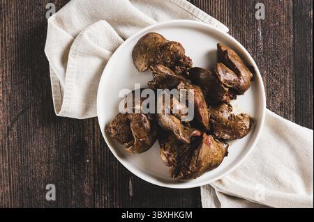 Essen, Nahaufnahme von Stücken gebratener Hühnerleber auf einem Teller auf dem Tisch von oben Stockfoto