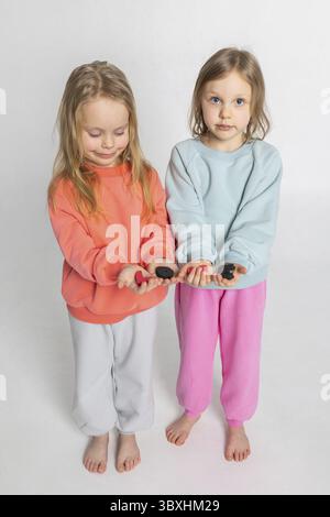 Zwei fröhliche hübsche Mädchen halten Briefe mit Wort LIEBE in den Händen. Vertikales Foto. Stockfoto
