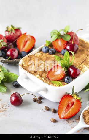 Essen, klassisches italienisches Dessert Tiramisu dekoriert mit Erdbeeren, Kirschen und Minze auf weißem Hintergrund Stockfoto