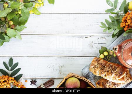 Essen, Backen mit Apfel, frisch gebackener Apfel und Zimtrollen aus Blätterteig auf einem weißen Holztisch Stockfoto