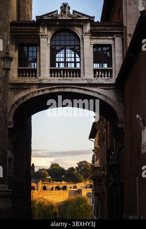 Durchgang zu den Ruinen unter einer alten Fußgängerbrücke zwischen zwei typischen Gebäude in Rom, Italien Stockfoto