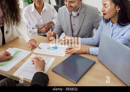 Verschiedene Gruppen von Fachleuten, die im Büro am Tisch sitzen und Dokumente und Diagramme überprüfen Stockfoto