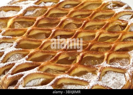 Großaufnahme einer köstlichen süßen Gittergalette mit knuspriger goldener Kruste, zarter Pudding-Schicht, karamelisierter Apfelfüllung und zartem Zuckerstaub Stockfoto