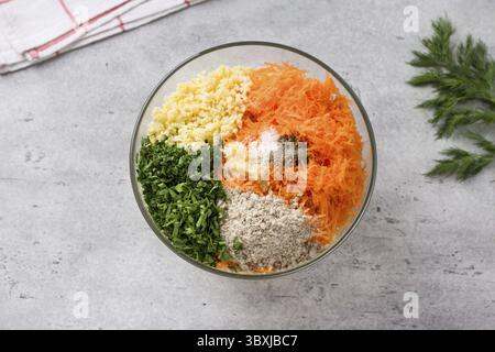 Essen, Glasschale mit Zutaten für vegane Schnitzel, Burger: Hirse, Karotten, Samen, Kräuter, Knoblauch und Gewürze mit einem Haufen frischen Dill, Blick von oben. S Stockfoto