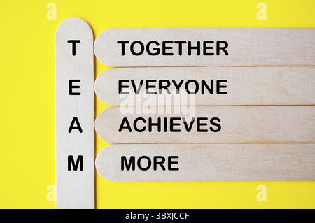 Draufsicht des TEAMTEXTES, der zusammen repräsentiert jeder erreicht mehr mit mehrfarbigen Holzstäben. Teamwork-Konzept Stockfoto