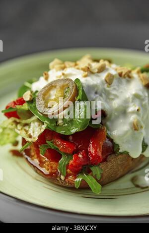 Gebackene Süßkartoffel mit Kirschtomaten, gebratenen Paprika, scharfer eingelegter Jalapeno-Scheibe, frischem Gemüse und Stracciatella mit gerösteter Haselnuss Stockfoto