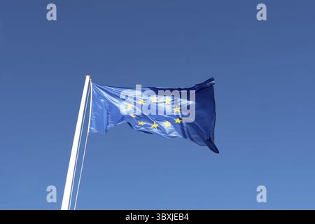 EU-Flagge - blaue Leinwand mit gelben Sternen wehen in blauen klaren Himmel Stockfoto