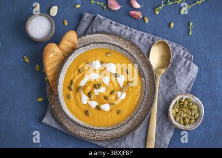 Puppmkin-Sahne-Suppenpüree auf dunkelblauem Holztisch, vegetarisches Mittagessen, Draufsicht Stockfoto
