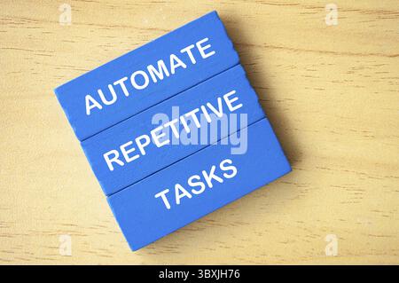 Draufsicht des Textes zur Automatisierung sich wiederholender Aufgaben auf blauen Holzblöcken. Konzept zur Verbesserung des Geschäftsbetriebs Stockfoto
