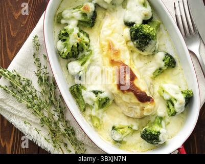 Hähnchenfilet gebacken mit Brokkoli in Bechamelsauce auf einem dunklen Holztisch. Gesundes Essen, sauberes Essen, Blick von oben Stockfoto