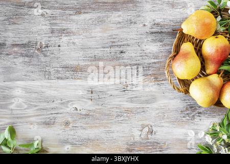 Essen, frische Birnen in einem Korb auf einem Holztisch. Draufsicht Stockfoto