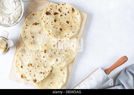 Essen, hausgemachte Weizentortillas, Pita Brot, Tortilla, Pita mit Zutaten zum Kochen auf einem weißen Tisch. Draufsicht. Das Konzept der hausgemachten Nahrung Stockfoto