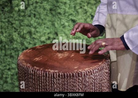 Afro-amerikanische Frau spielt afrikanische ethnische Schlagzeug. Schlagzeuger spielt afrikanische Musik auf Instrument Djembe. Nahaufnahme von Menschenhänden. Stockfoto
