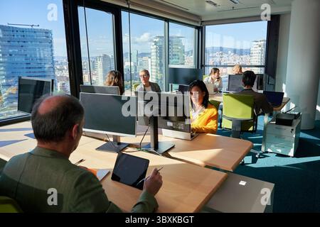 Business-Team arbeitet an Computern in modernen Büros mit Stadtblick. Stockfoto