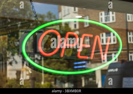 Bright neon OPEN sign in shop window with green oval border Stockfoto