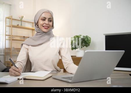 Junge muslimische Geschäftsfrau Buchhalterin, die mit Rechnungen für Finanzdokumente arbeitet, Steuern berechnen. Frau muslimische Freiberuflerin Papierkram zu Hause Stockfoto