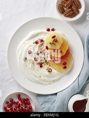 Ricotta mit Zitrusfrüchten, Pekannüssen. Gemischter Salat mit Kokosjoghurt. Süßes und gesundes buntes Dessert mit Joghurt und Granatapfelkernen. Vertikal, Stockfoto