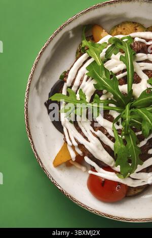 Köstliches gegrilltes Rindersteak, serviert mit gegrilltem Gemüse, frischem Rucola und cremiger Joghurtsauce für eine gesunde und geschmackvolle Mahlzeit Stockfoto