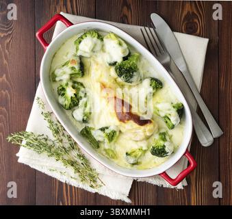 Hähnchenfilet gebacken mit Brokkoli in Bechamelsauce auf einem dunklen Holztisch. Gesundes Essen, sauberes Essen, Blick von oben Stockfoto
