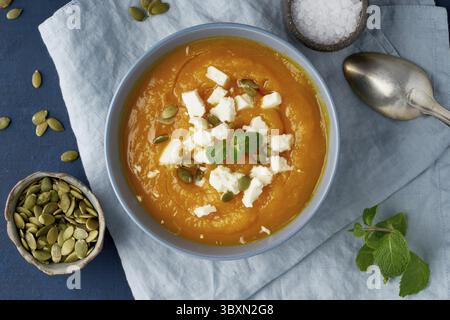 Kürbis-Creme-Suppe mit Schafskäse, herbstliche hausgemachte Speisen, dunkelblauer Hintergrund, Blick von oben. FODMAP-Diät, lchf. Vegetarisches Menü, sauberes Rezept Stockfoto