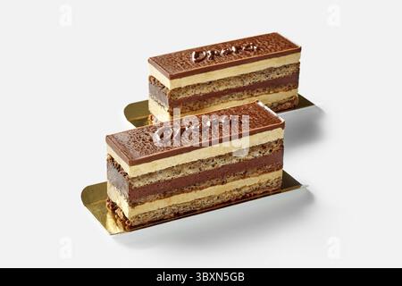 Kuchenscheiben mit Schichten von Walnussschwammteig, eingeweicht in Kaffeesirup, Schokoladenganache und Buttercreme, mit dem Wort Opera auf Schokoladenglasur geschrieben Stockfoto