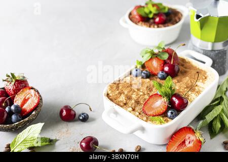 Essen, Tiramisu dekoriert mit Erdbeeren, Kirschen und Minze auf weißem Hintergrund Stockfoto